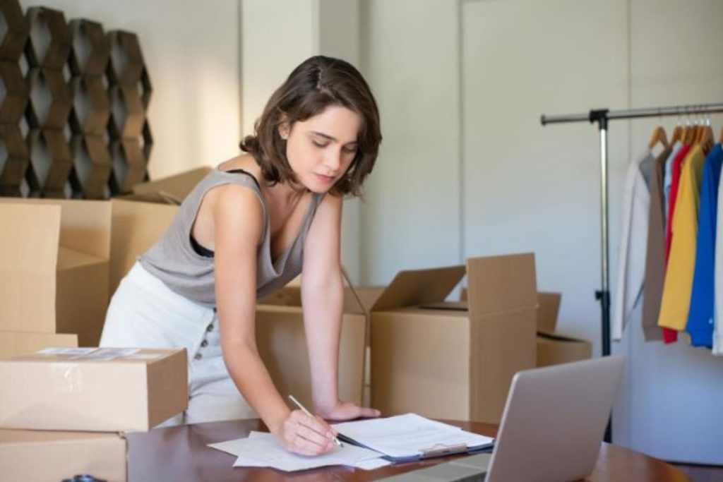 woman standing at a desk writing on a clipboard