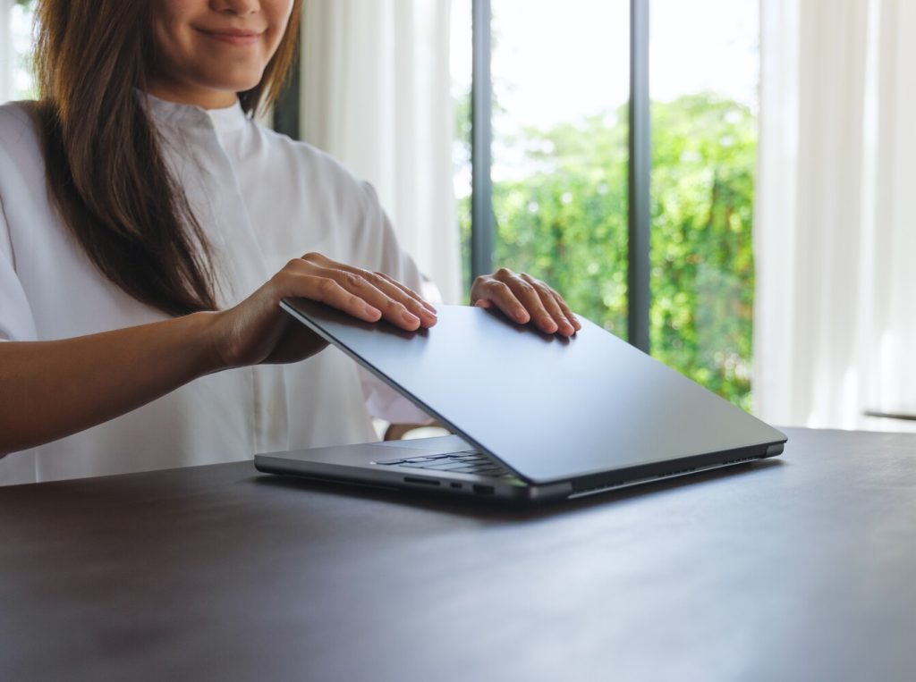 Closeup image of a woman opening or closing laptop computer, getting ready for work