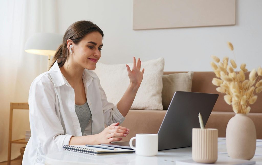 woman in front of a computer screen waving 
