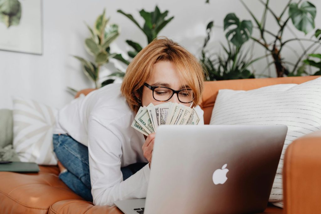 person kneeling in front of a computer holding money