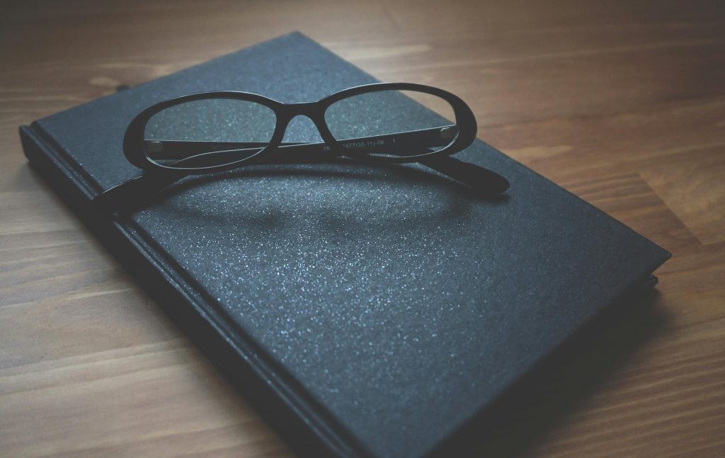 closed notebook with reading glasses folded on top