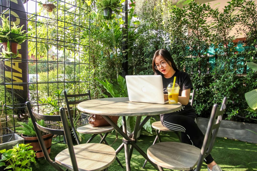young woman sitting in a cafe surrounded by greenery