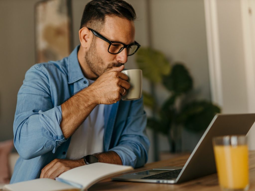 Focused freelancer enjoying coffee while working from home office