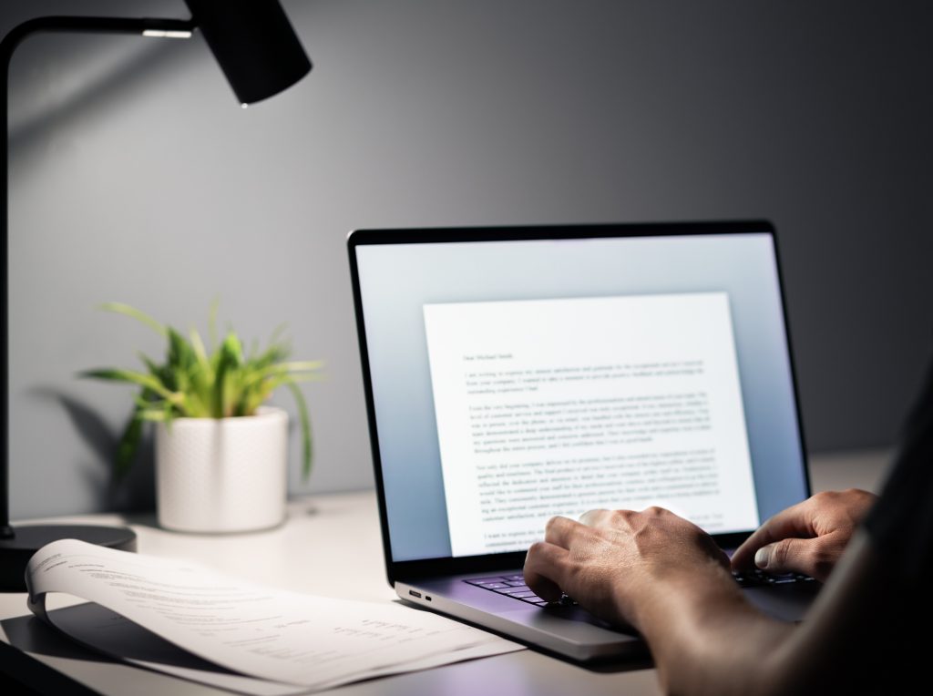 Man writing text document, essay or letter with laptop. Freelance writer, journalist or entrepreneur working late at night, overtime. Job seeker, cv resume and application. Dark home or office room.