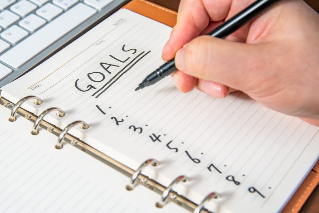 man writing goals on a notepad