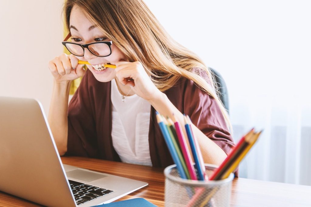 woman biting a pencil while reading online