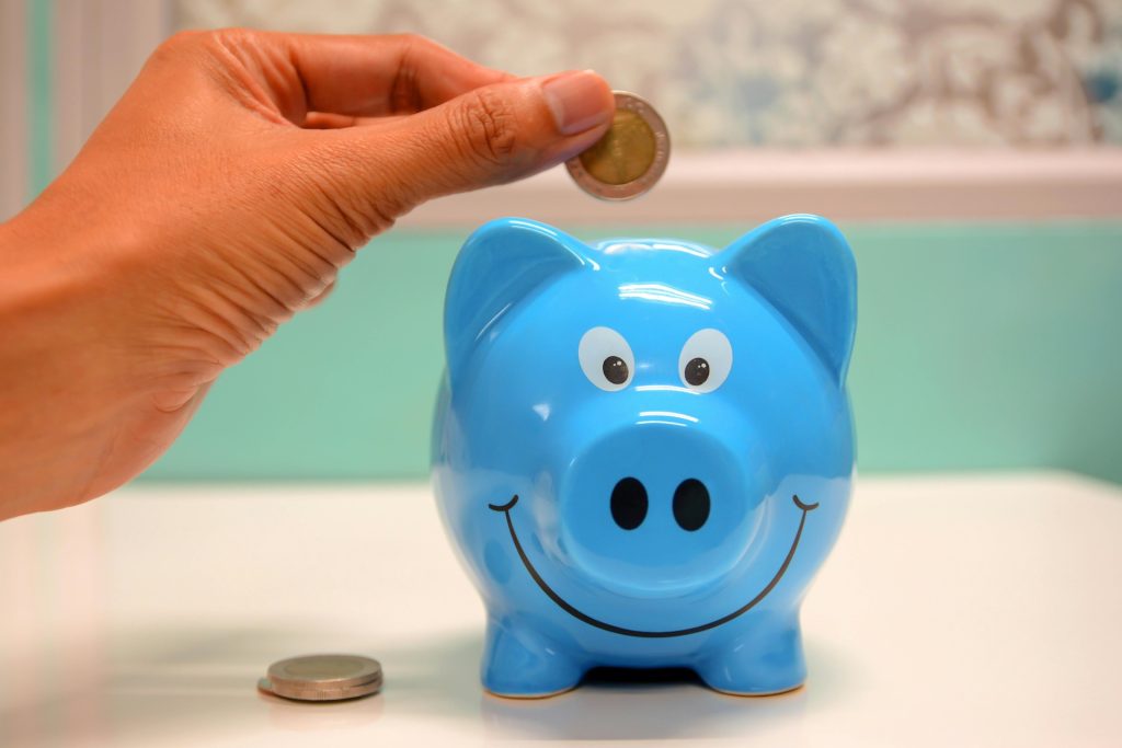 saving coins in a blue piggy bank