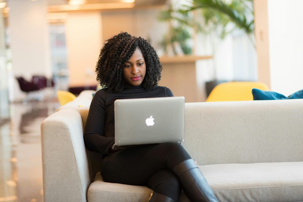 woman on couch working on laptop at proofreading