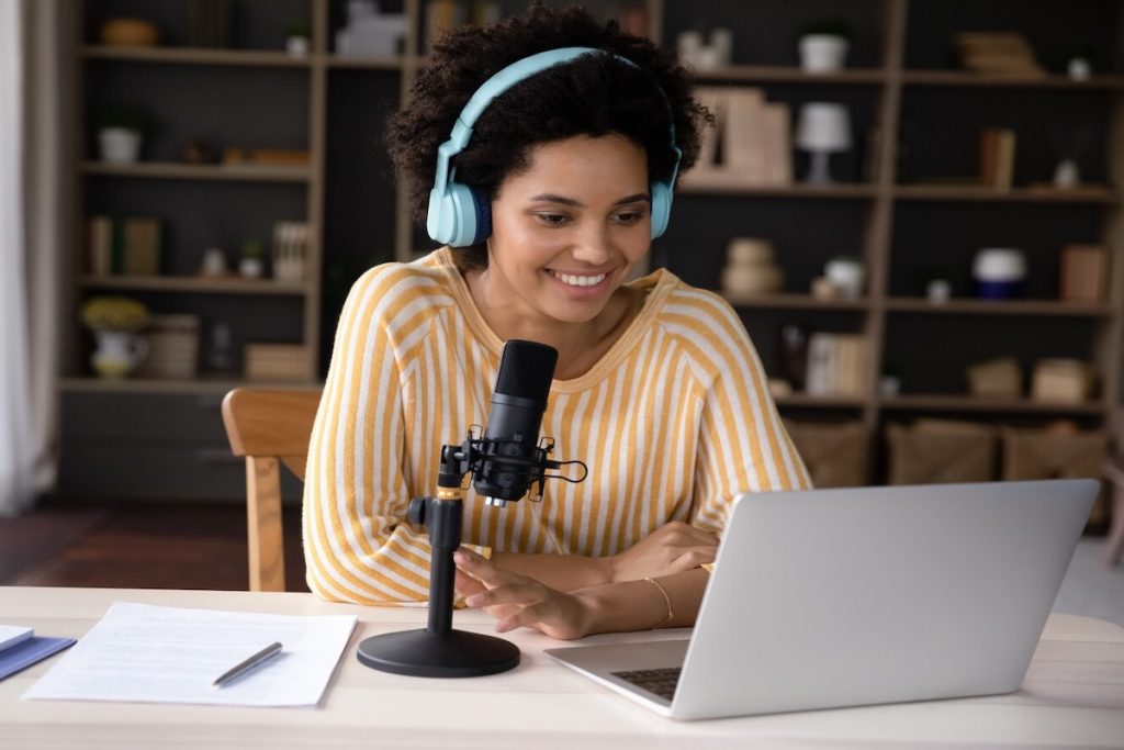 woman wearing headphones and recording sound on laptop