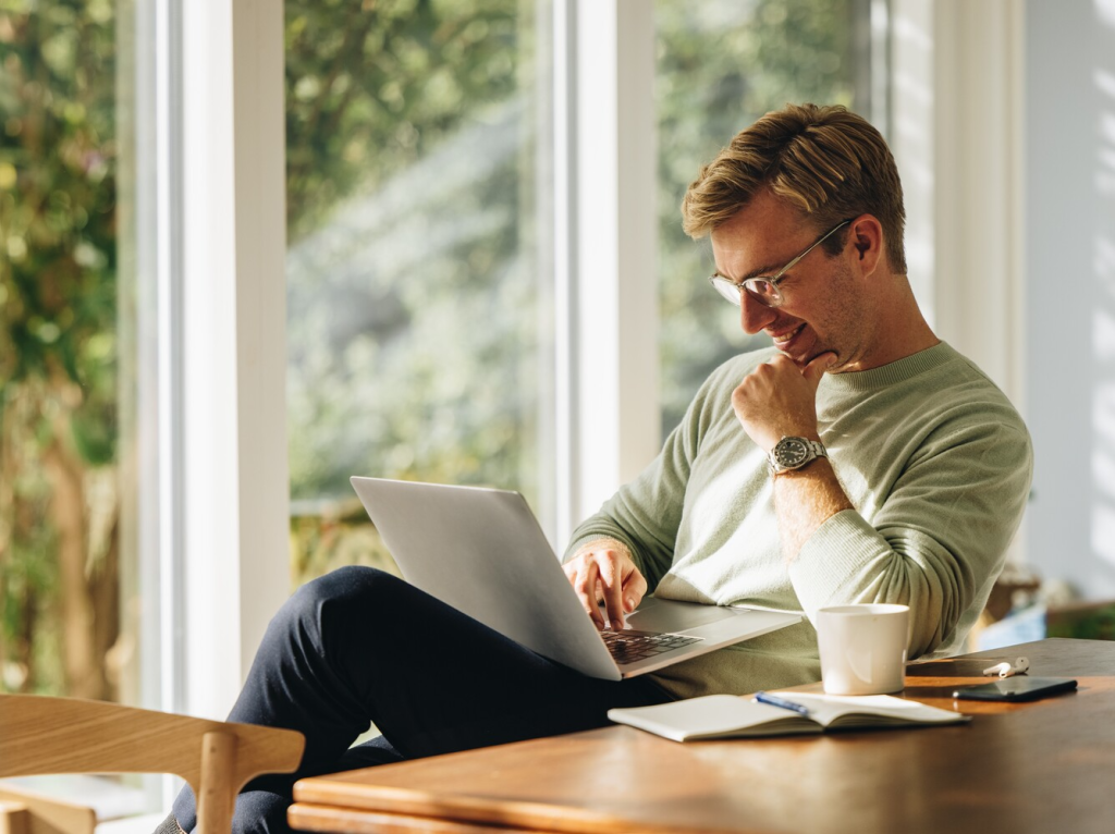 man smiling while working on a laptop